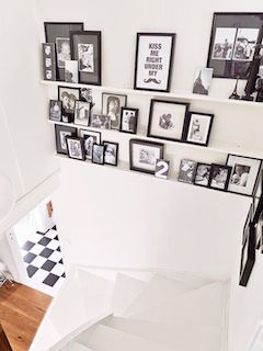 黒のフォトフレームでたくさんの写真を飾ったモノトーンな階段の画像