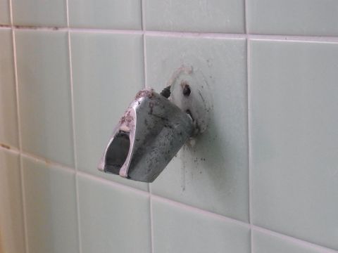 壁から取れかかっているシャワーフック。